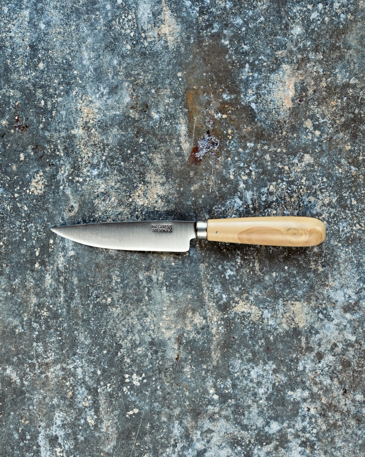 Small knife with a wooden handle on a textured stone surface