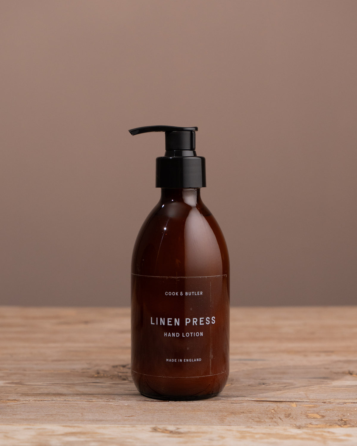 Brown bottle with black pump on a wooden surface and brown background