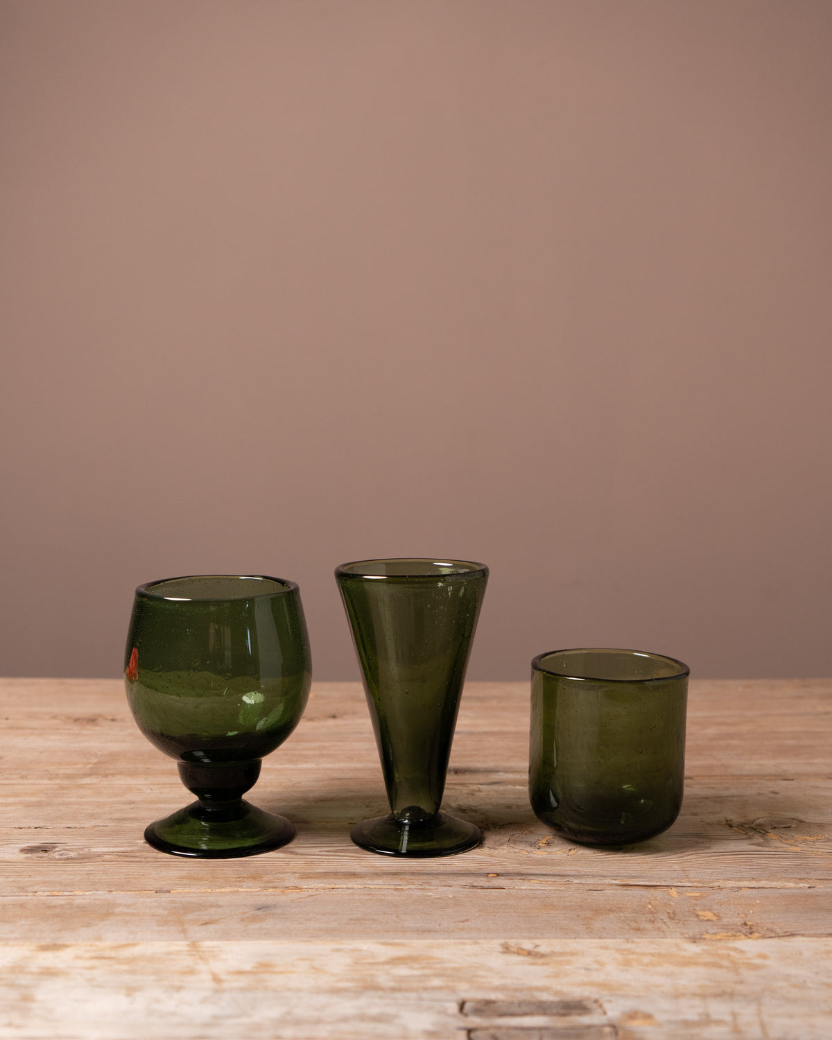Three Recycled green drinking glasses on a wooden table