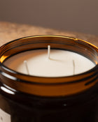 A candle with three wicks with a brown background.