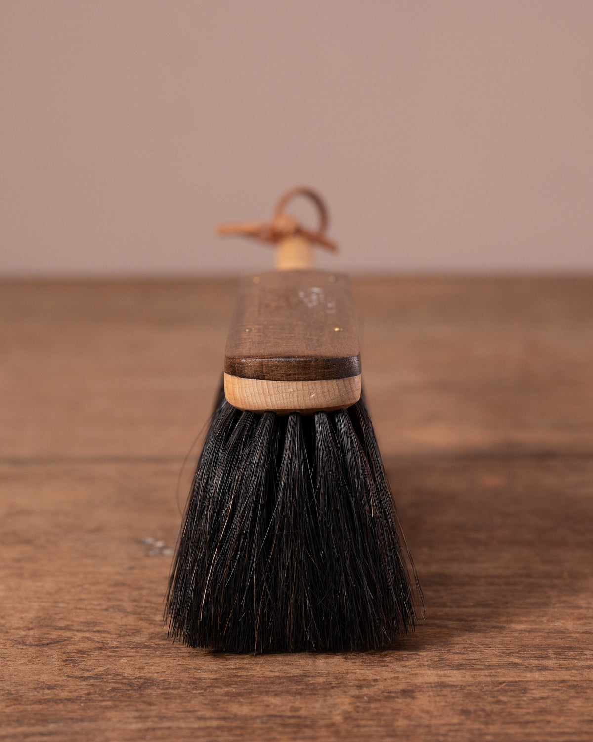 Duster brush with wooden handle on a wooden surface