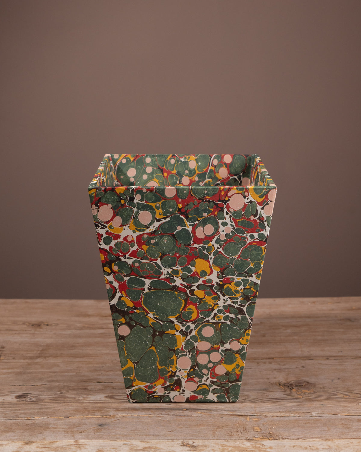 Decorative bin with a multicolored pattern on a wooden surface and brown background