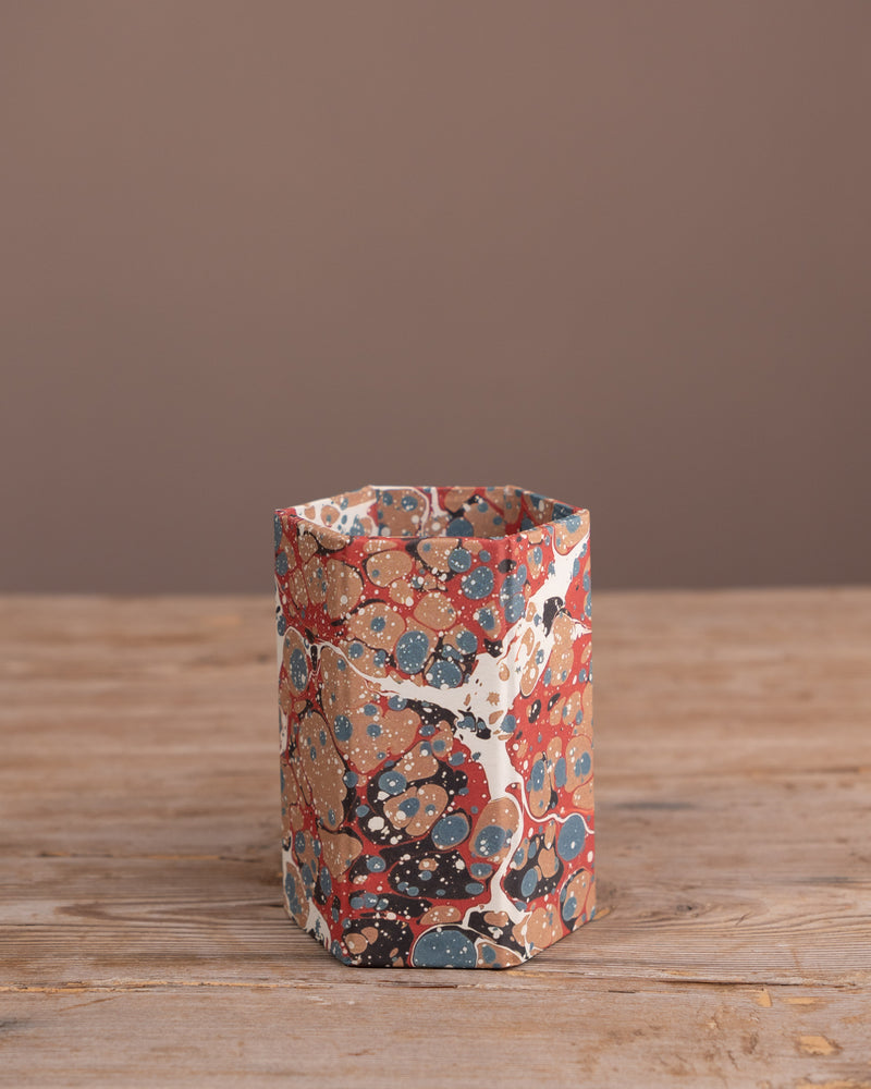 Marbled hexagonal pen pot on a wooden surface with a brown background