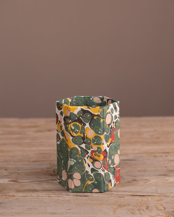 Colorful patterned pen pot on a wooden surface with a brown background