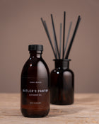 Brown diffuser oil bottle with black cap on a wooden surface, featuring 'Butler's Pantry' branding.