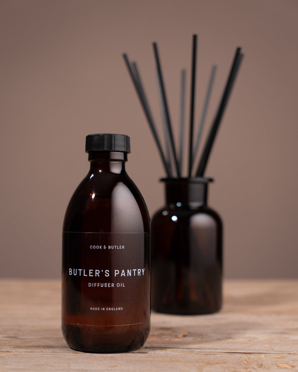 Brown diffuser oil bottle with black cap on a wooden surface, featuring 'Butler's Pantry' branding.