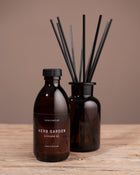 Brown diffuser bottle with black label and black reeds on a wooden surface against a brown background