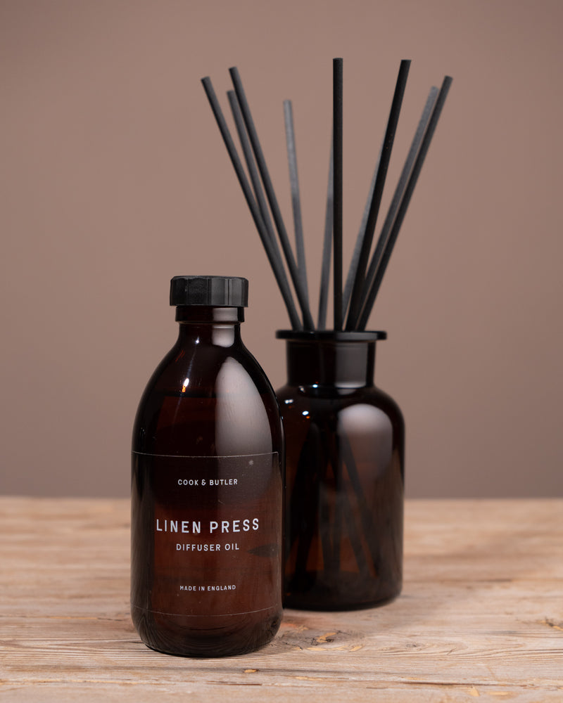 Diffuser oil bottle labeled 'Geranium Leaf' with black reeds on a wooden surface and brown background