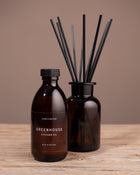 Diffuser oil bottle and reed diffuser on a wooden surface with a brown background