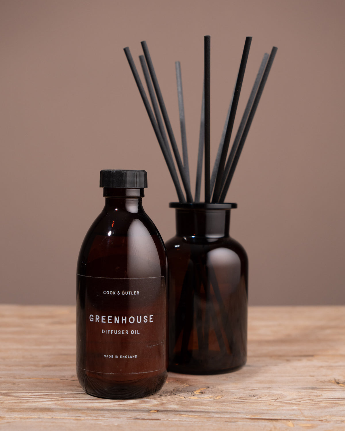 Diffuser oil bottle and reed diffuser on a wooden surface with a brown background