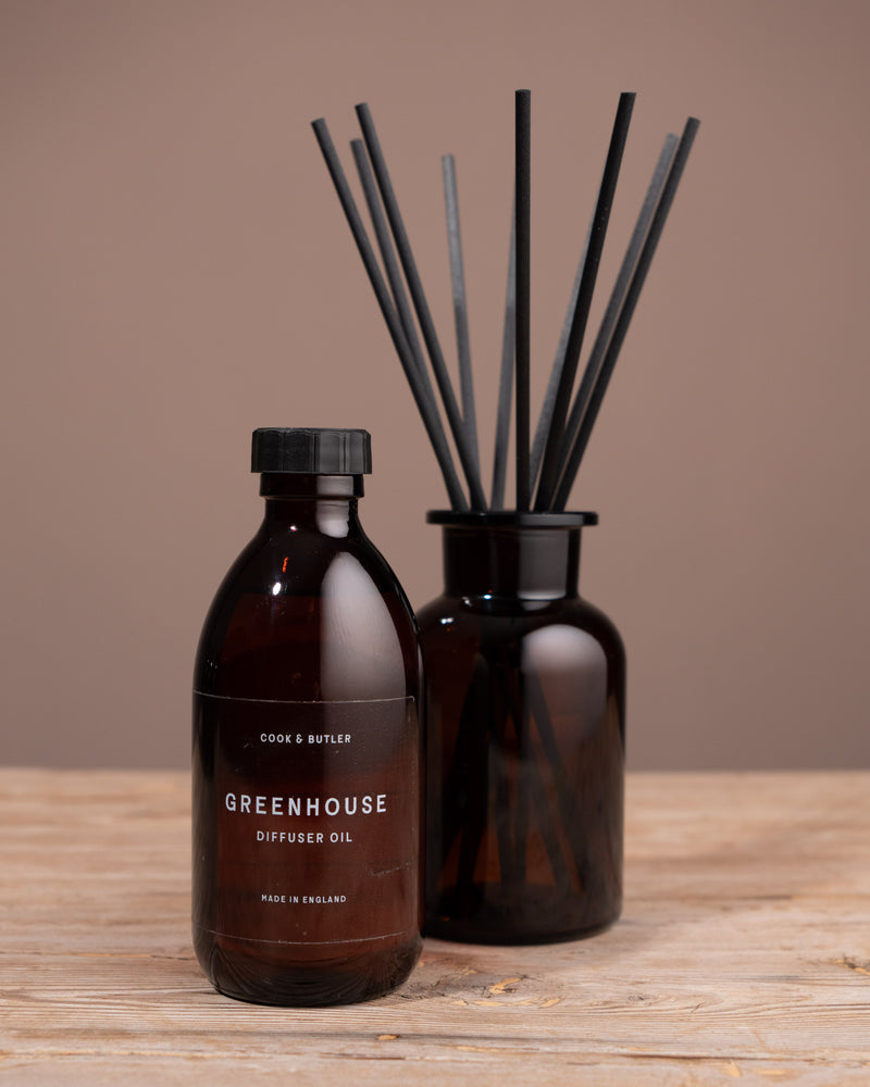 Diffuser oil bottle and reed diffuser on a wooden surface with a brown background
