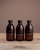 Three diffuser oil bottles from Caudle & Co. on a wooden surface with a brown background