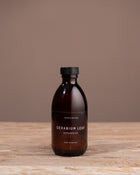 Bottle of Geranium Leaf diffuser oil on a wooden surface with a brown background