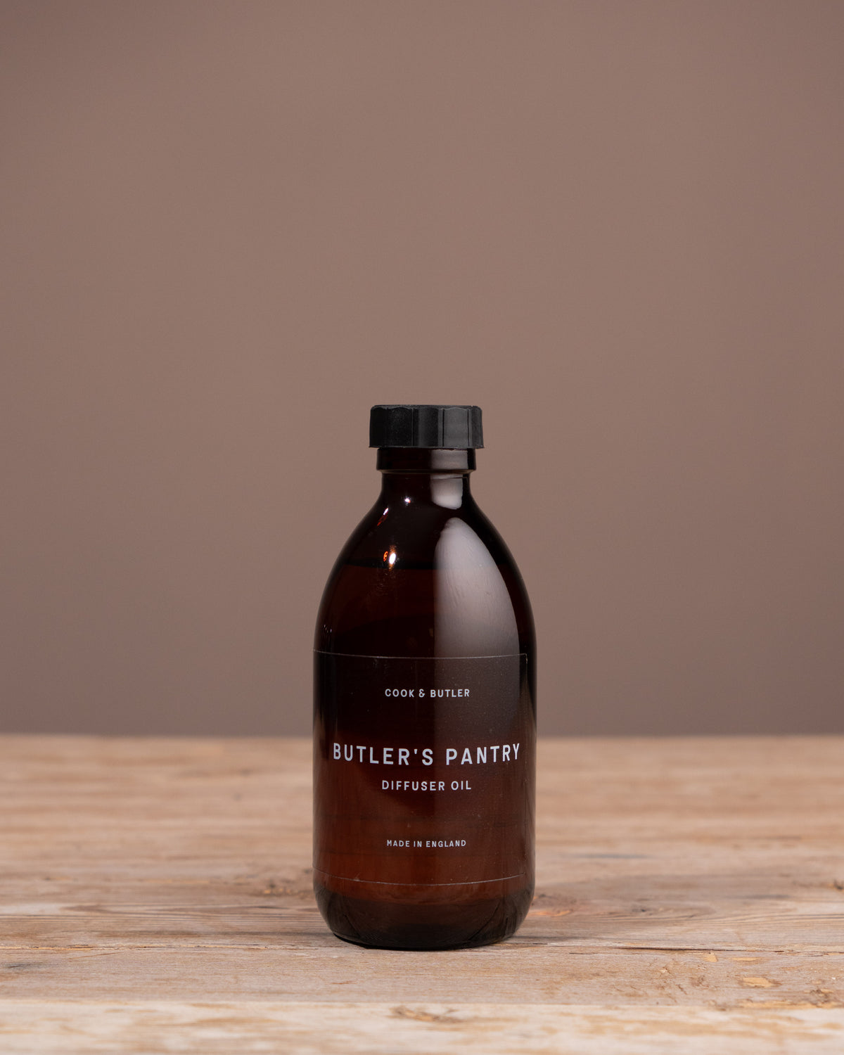Brown bottle with black cap on a wooden surface and brown background