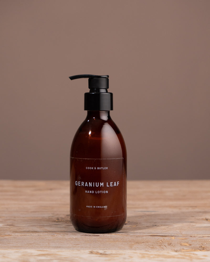 Cook & Butler hand lotion bottle with pump on a wooden surface and brown background