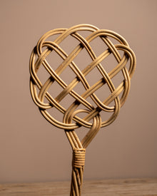 Woven rattan heart-shaped object on a wooden surface with a brown background
