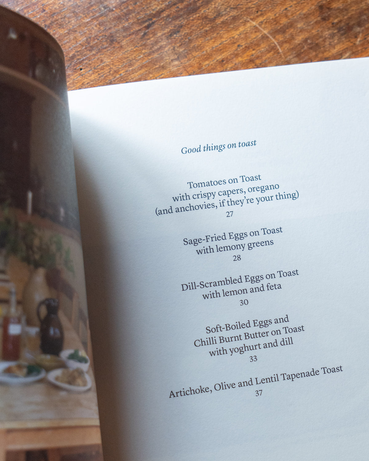 Cookbook titled 'Midweek Recipes' by Jess Elliott Dennison opened on a wooden able