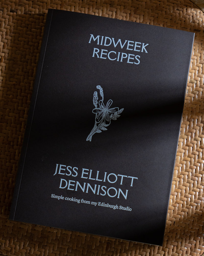 Cookbook titled 'Midweek Recipes' by Jess Elliott Dennison on a woven surface
