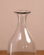 Clear glass carafe on a wooden surface with a beige background