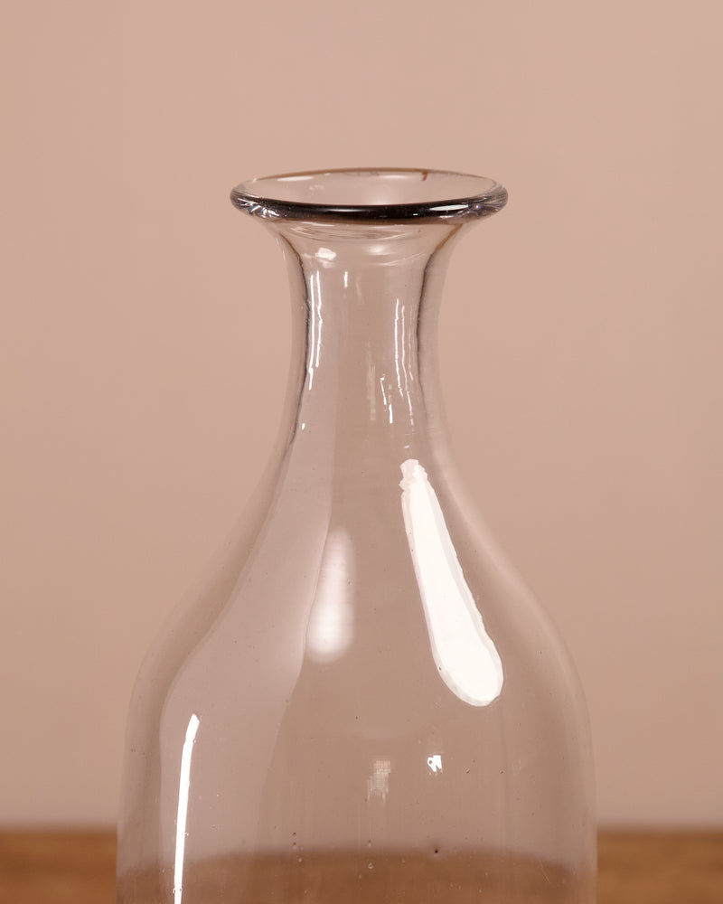 Clear glass carafe on a wooden surface with a beige background