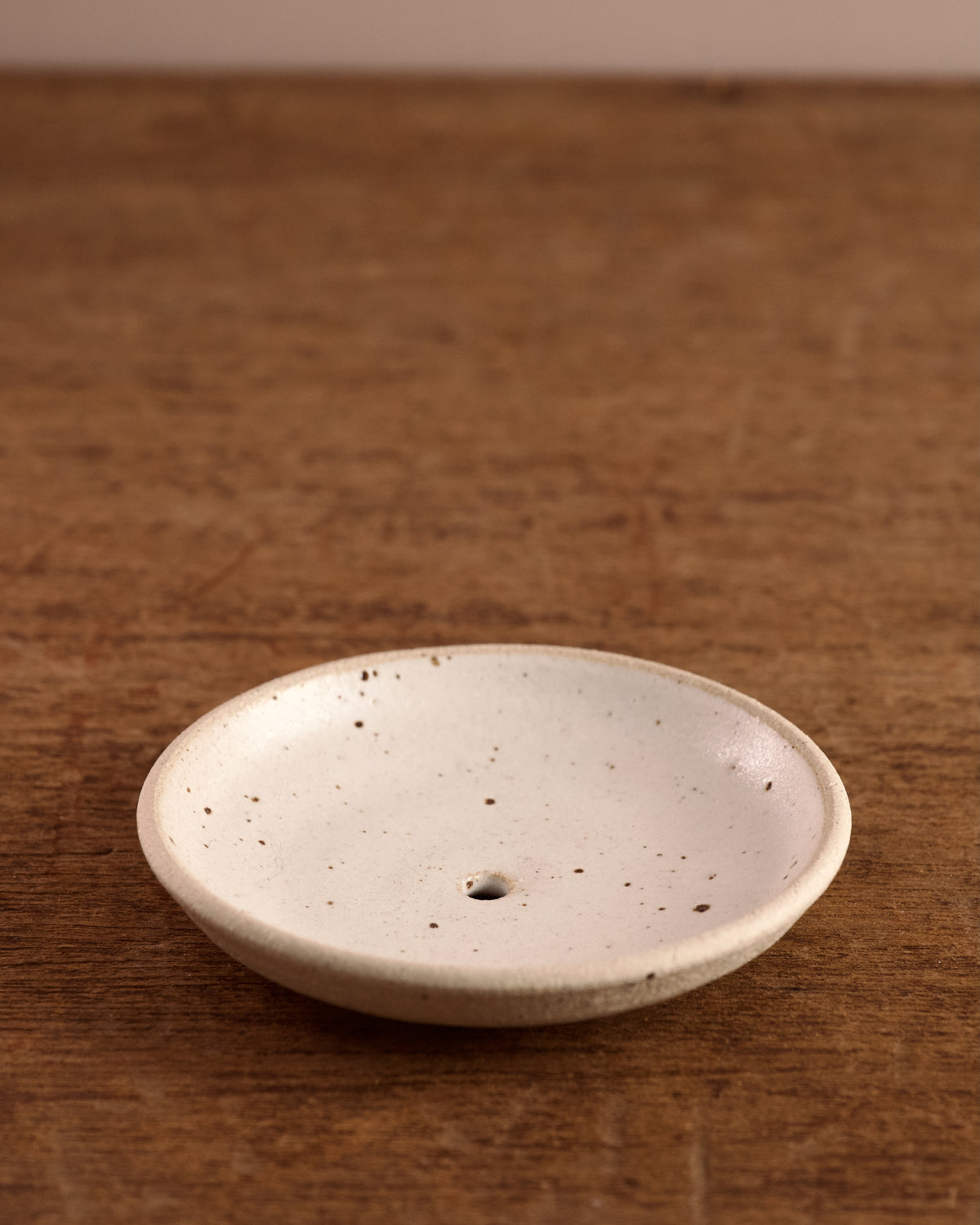 Speckled ceramic soap dish on a wooden surface