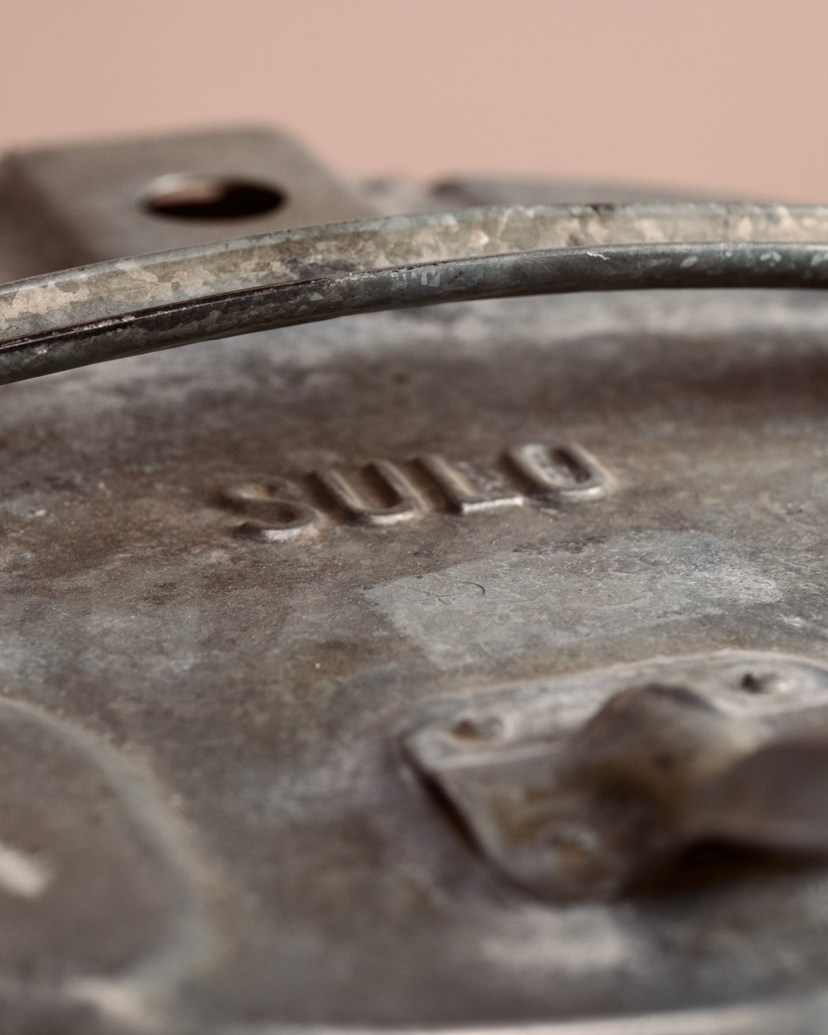 Vintage-style metal ash can on a wooden surface with a beige background