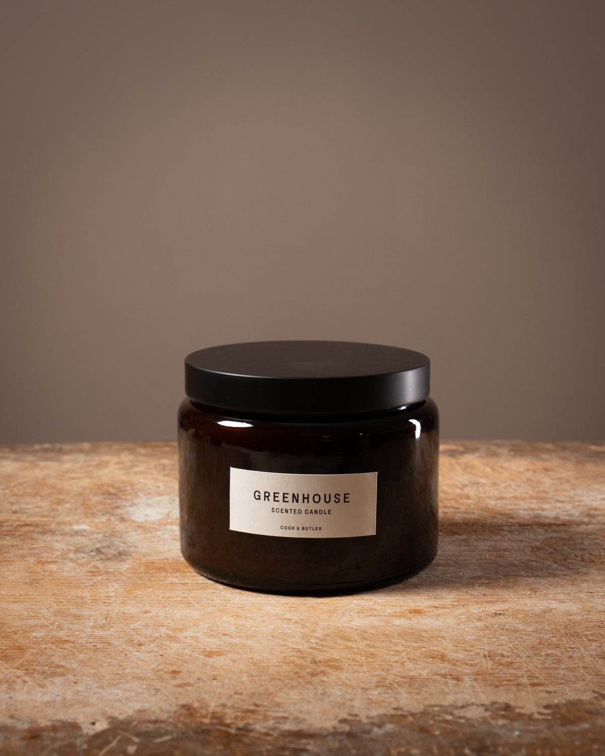 Cook and Butler scented candle on a wooden worktop with a label saying "greenhouse"