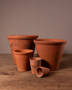 Set of terracotta pots on a wooden surface with a brown background