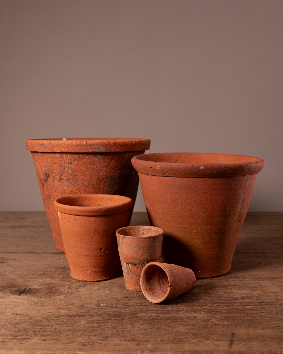 Set of terracotta pots on a wooden surface with a brown background