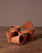 Set of terracotta pots on a wooden surface with a brown background