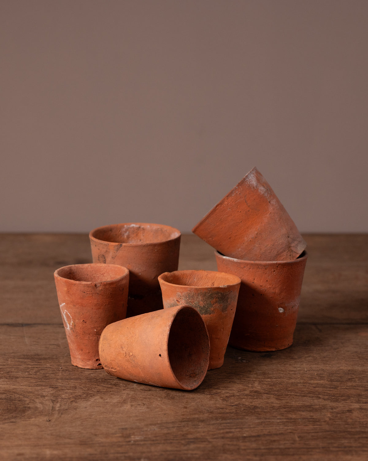 Set of terracotta pots on a wooden surface with a brown background