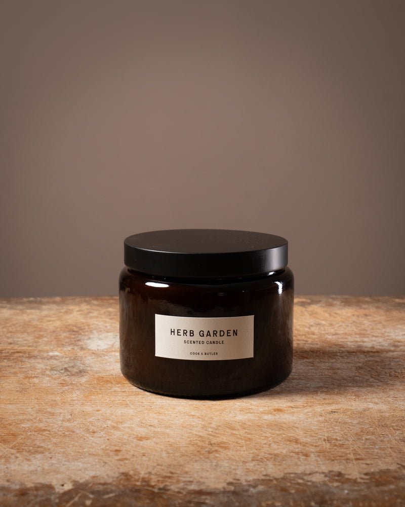 Cook and Butler scented candle on a wooden worktop with a label saying "herb garden"