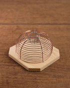 Lobster pot-style mouse trap with copper wire on a wooden base
