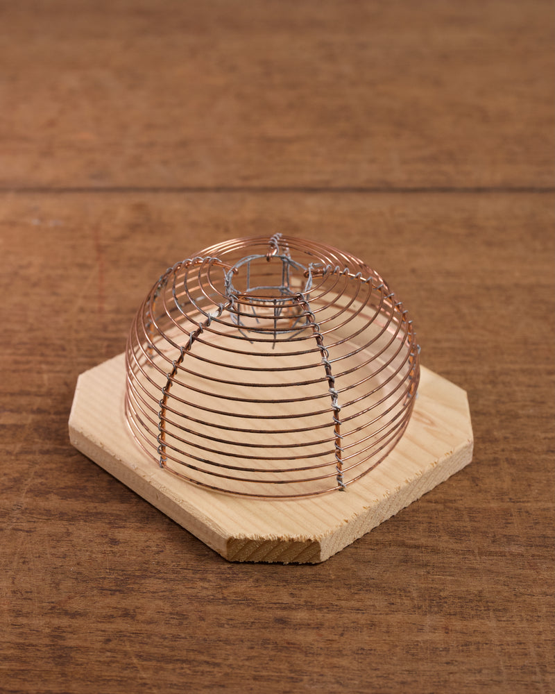 Lobster pot-style mouse trap with copper wire on a wooden base
