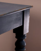 Close-up of a dark wooden table leg against a brown background