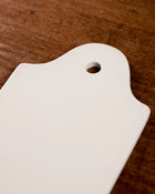 White ceramic cutting board with a hole on a wooden surface