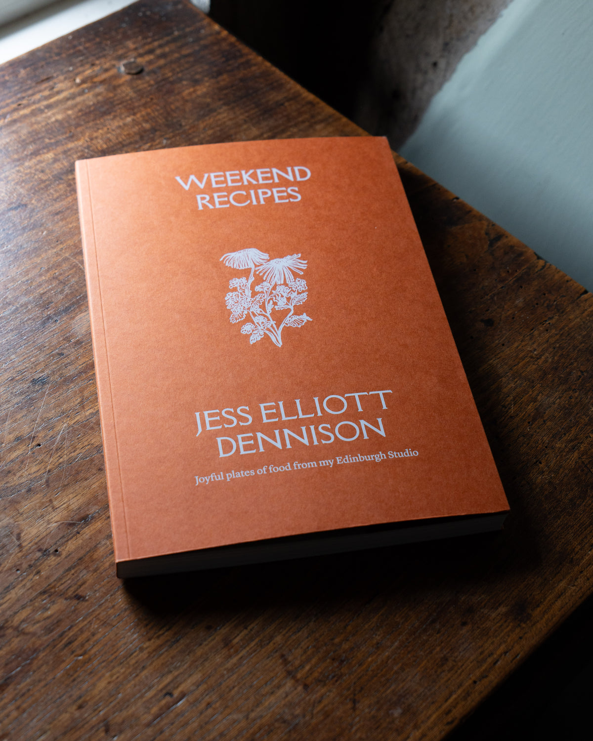 Cookbook titled 'Weekend Recipes' by Jess Elliott Dennison on a wooden surface