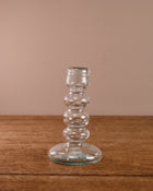 Clear glass candle holder on a wooden surface with a beige background
