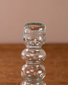 Clear glass candle holder on a wooden surface with a beige background