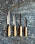 Set of four knives with wooden handles on a textured stone surface