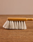 Wooden cleaning brush with white bristles on a wooden surface