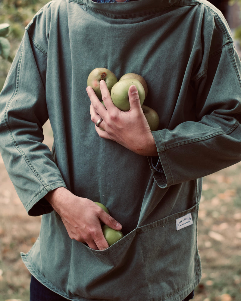 Person holding green apples in an orchard