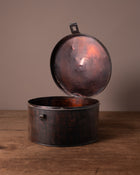 Vintage-style metal hat box with open lid on a wooden surface