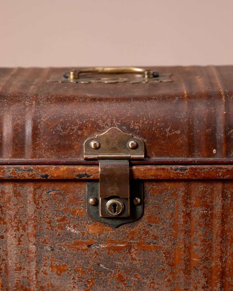 Close-up of an old, rusty suitcase with a lock on a beige background