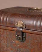 Close-up of an old, rusty suitcase with a brass lock on a brown background