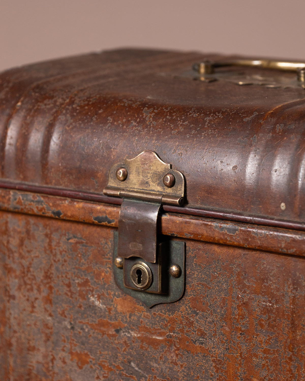 Close-up of an old, rusty suitcase with a brass lock on a brown background