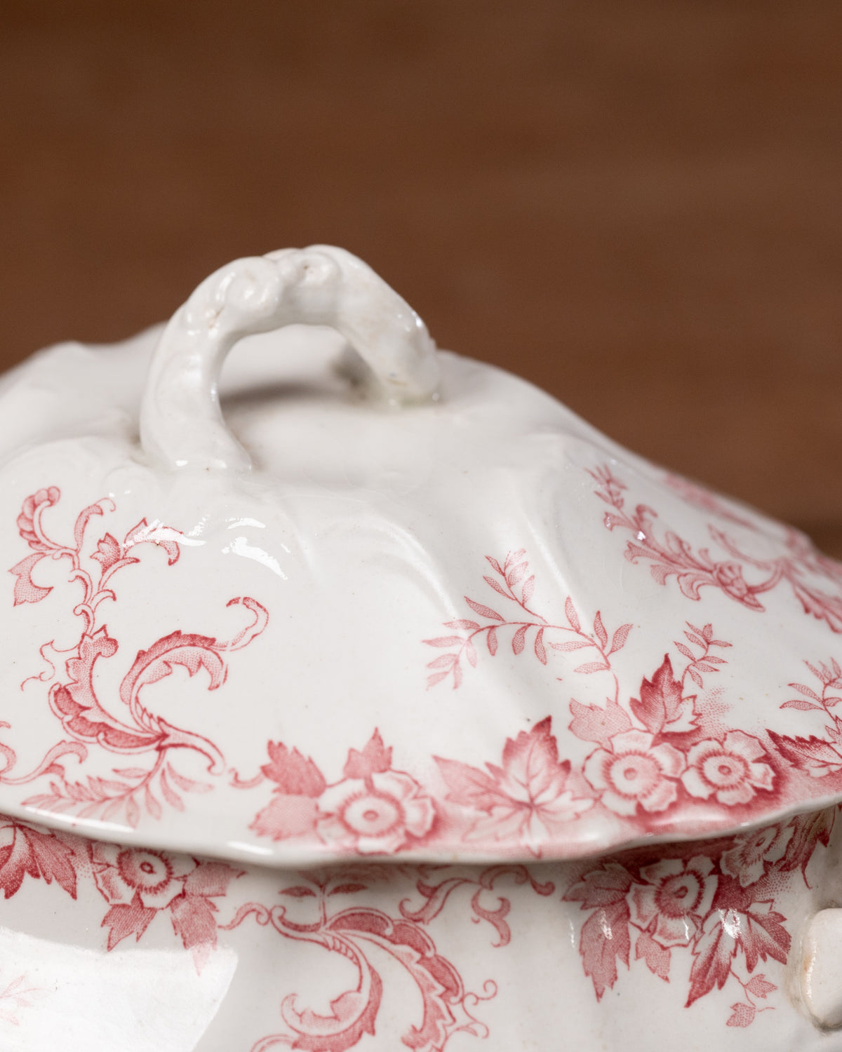 White ceramic tureen with red floral patterns on a brown background