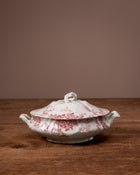 White ceramic tureen with red floral pattern on a wooden surface