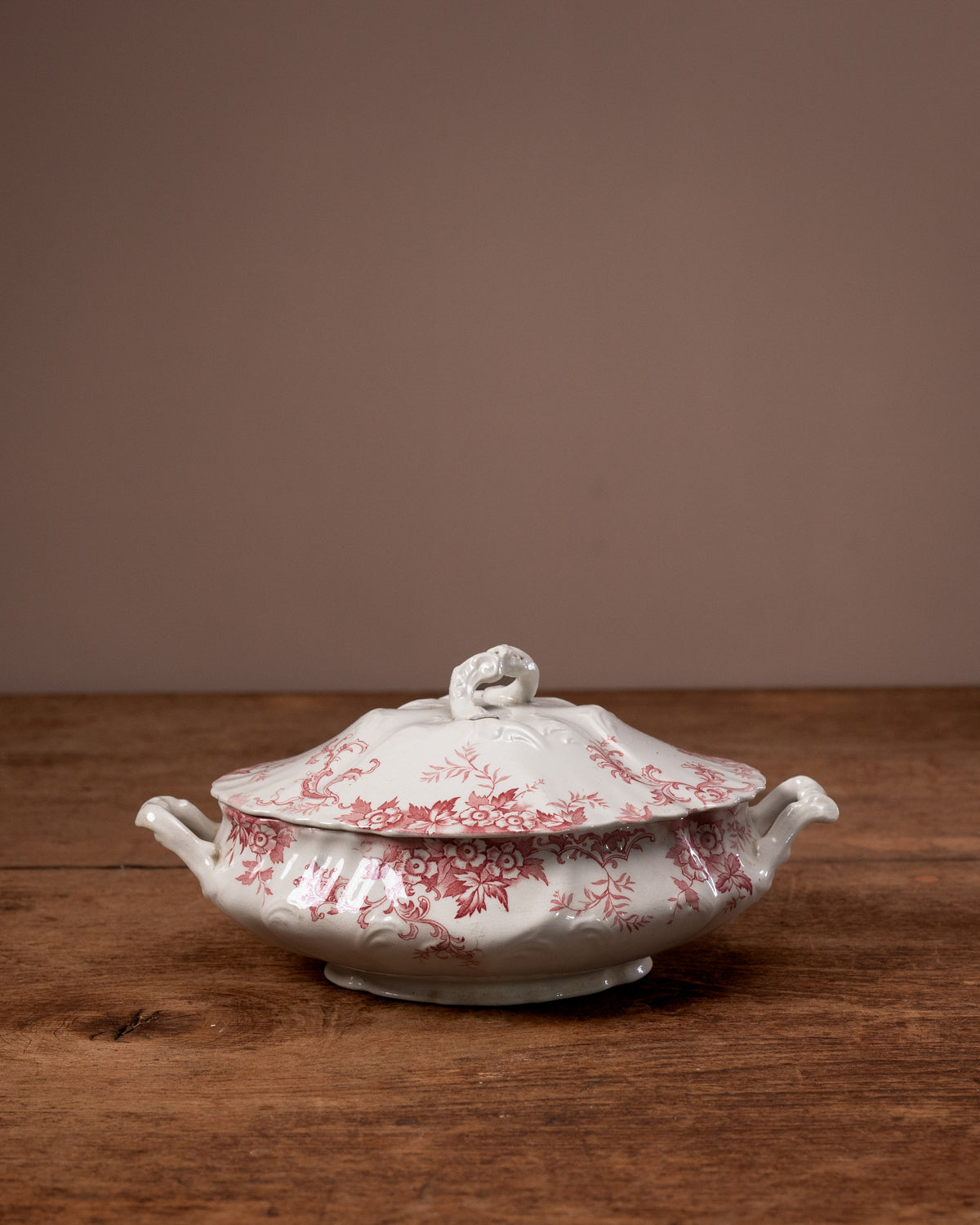 White ceramic tureen with red floral pattern on a wooden surface