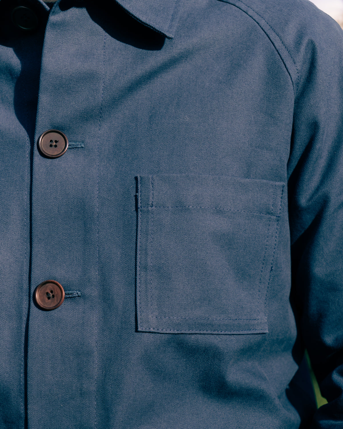 Close-up of a blue work jacket with buttons and a pocket